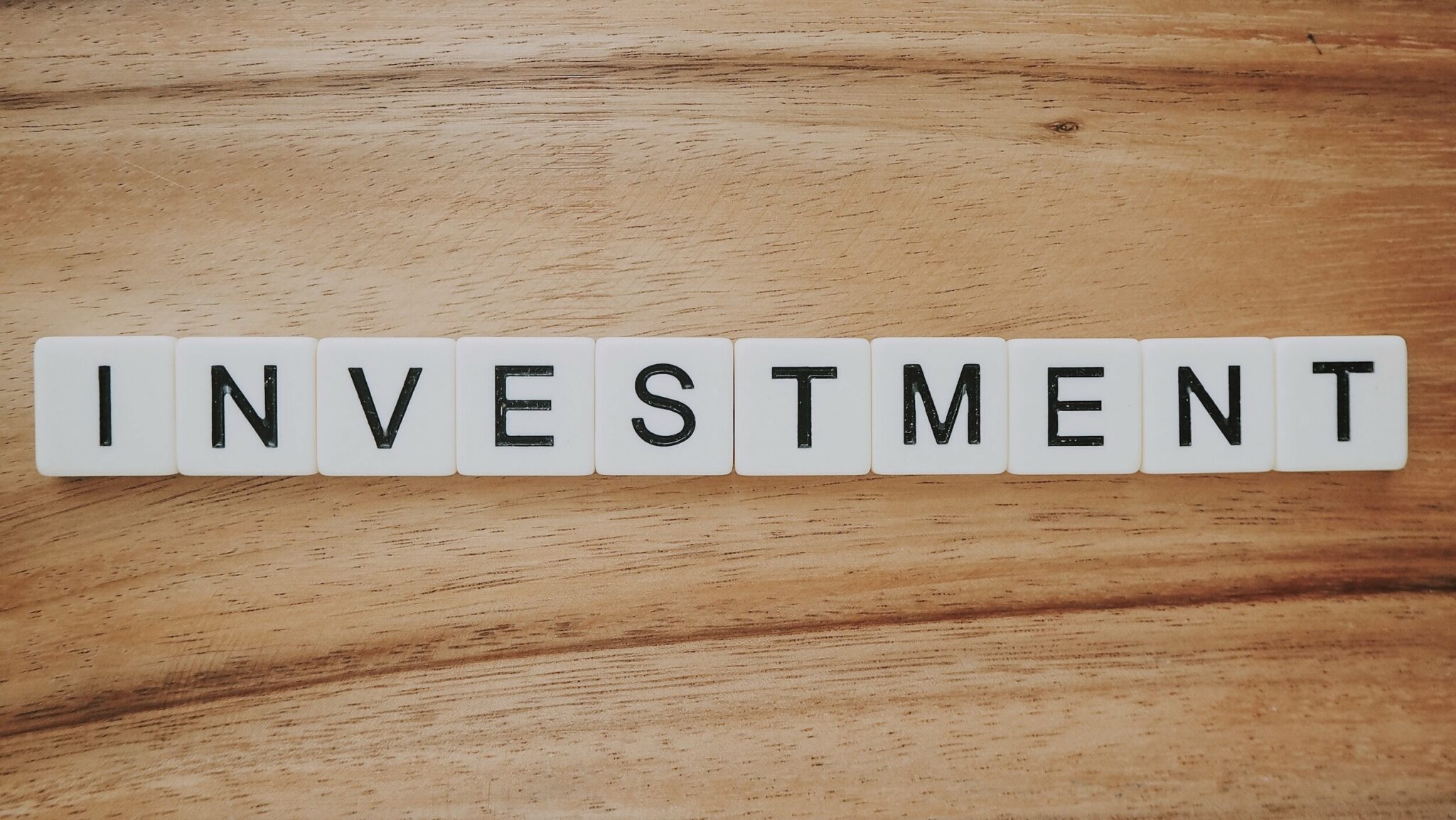 Scrabble pieces spelling out "INVESTMENT"