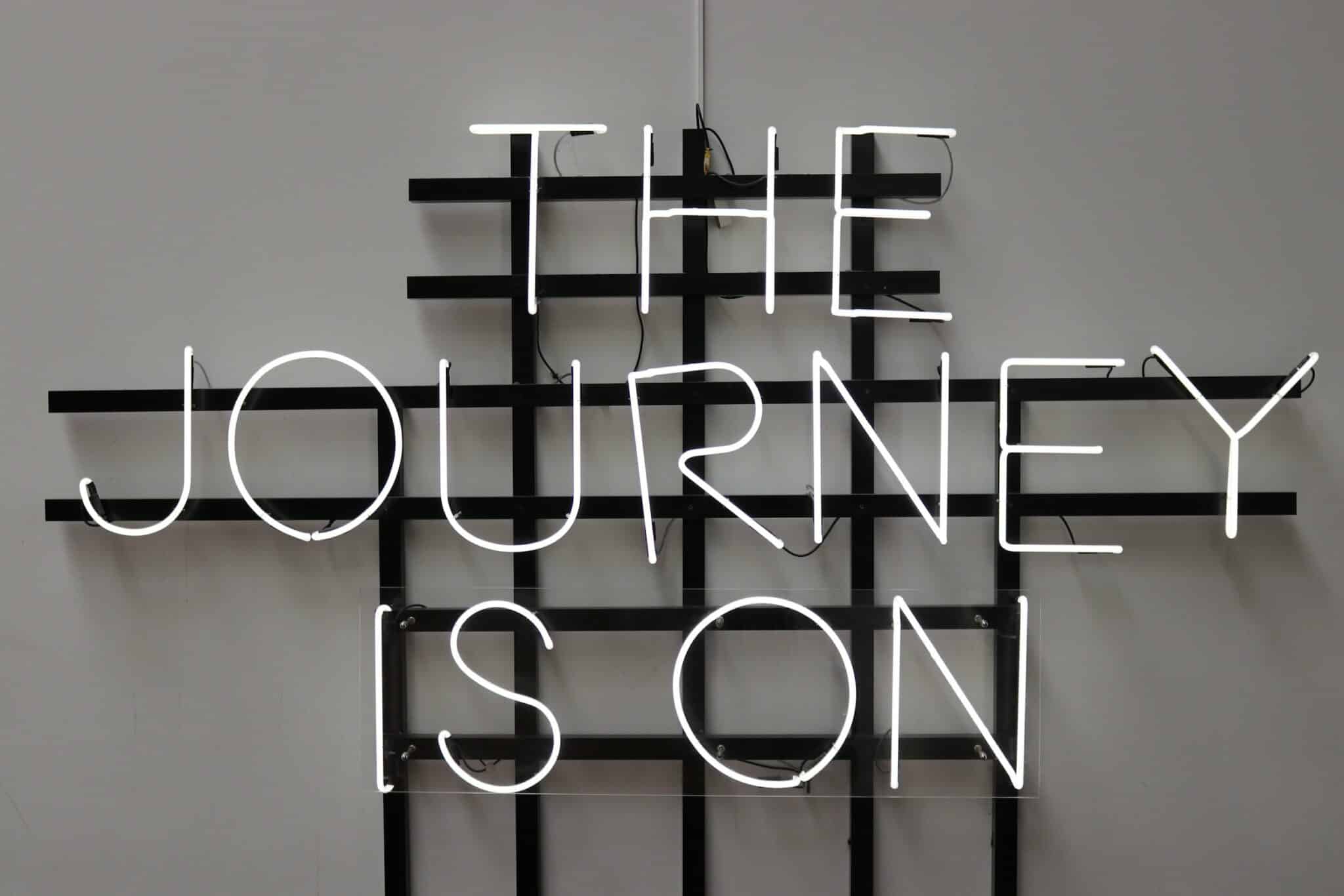 Neon sign with the words "The Journey Is On"