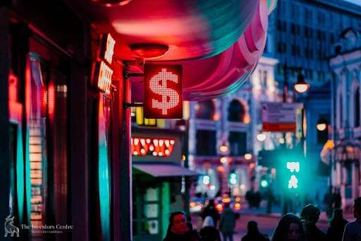 City street at night illuminated by neon dollar sign, symbolising digital wealth, urban finance, and passive income opportunities with NFTs and crypto assets in 2025